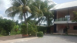 A two-story building with a balcony, surrounded by palm trees and greenery. - Charlee House (Trang)