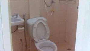A small bathroom with a toilet, sink, and shower. - Charlee House (Trang)