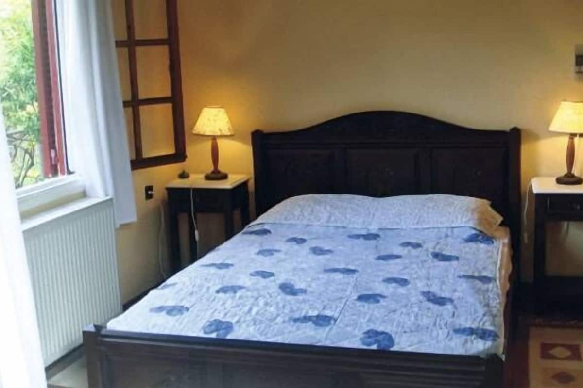 Une chambre à coucher avec un lit, deux lampes de chevet, une fenêtre et un radiateur.