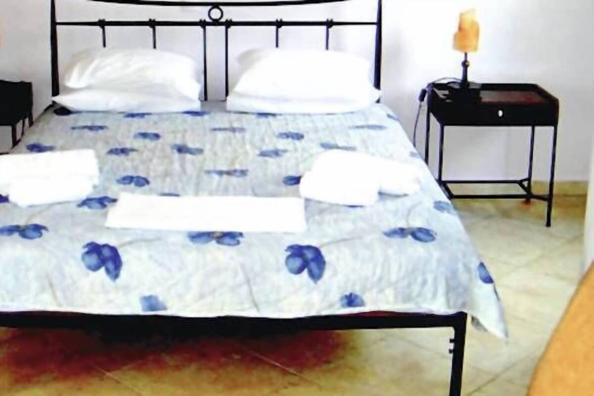Un lit avec une couvre-lit à motifs floraux, deux oreillers et deux tables de chevet avec des bougies.