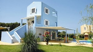 Una casa de dos pisos con un porche cubierto y una piscina.