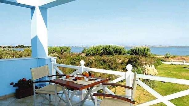 Balcón con mesa y sillas con vista a un paisaje costero.