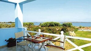 A balcony with a table and chairs overlooking a coastal landscape. - Gyra Villas (Lefkada)