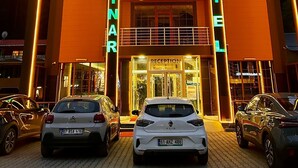 Un hotel con estructura de dos pisos, una zona de recepción y varios coches estacionados al frente.