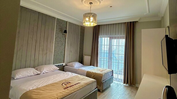 Habitación de hotel con dos camas, un escritorio, un televisor y una ventana con cortinas.