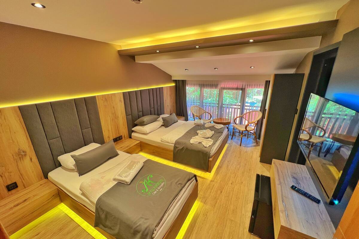 A modern hotel room with two beds, a TV, and a balcony with a view.