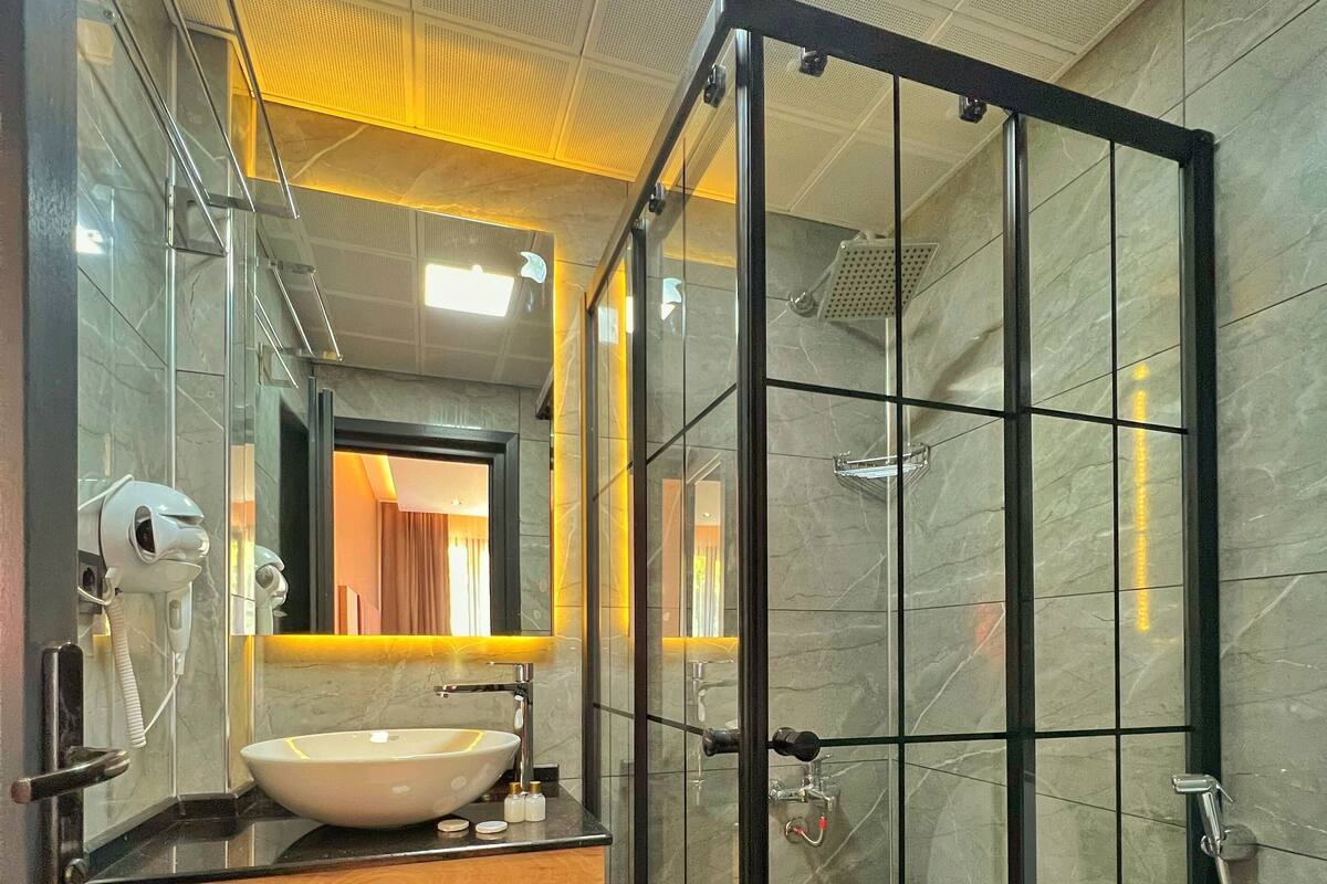 A modern bathroom with a glass-enclosed shower, a wooden vanity, and a large mirror.