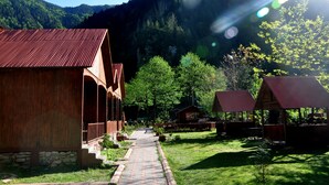 A rustic lodge with a stone foundation, wooden exterior, and a brick pathway leading to the entrance. - Akyuz Kardesler Hotel & Bungalow (Çaykara)