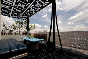 A rooftop terrace with a blue table, black chairs, a black sofa, and a decorative metal ceiling. - Monthara Angkor Residence (Siem Reap)