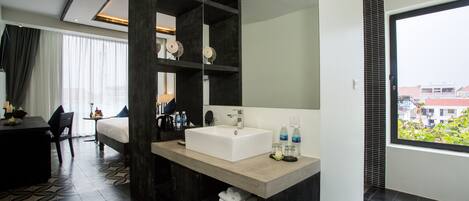 A modern bathroom with a large sink, dark wood shelving, and a view of the city through a large window.