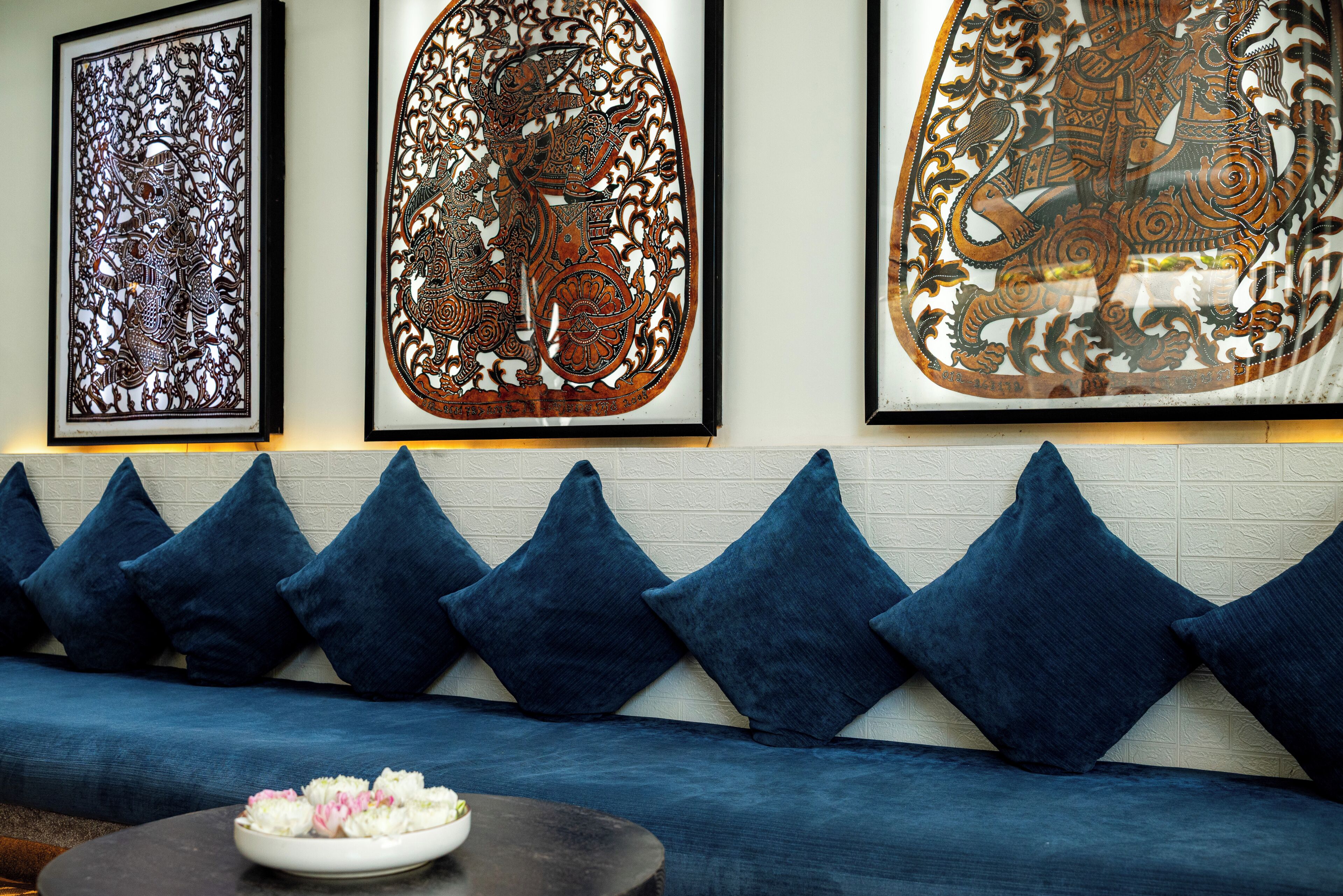 Ein Zimmer mit einem blauen Sofa, Wandkunst und einer Schale Blumen auf einem Tisch.