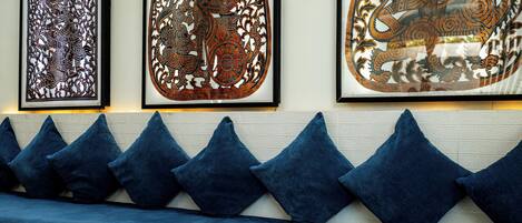 Ein Zimmer mit einem blauen Sofa, Wandkunst und einer Schale Blumen auf einem Tisch.