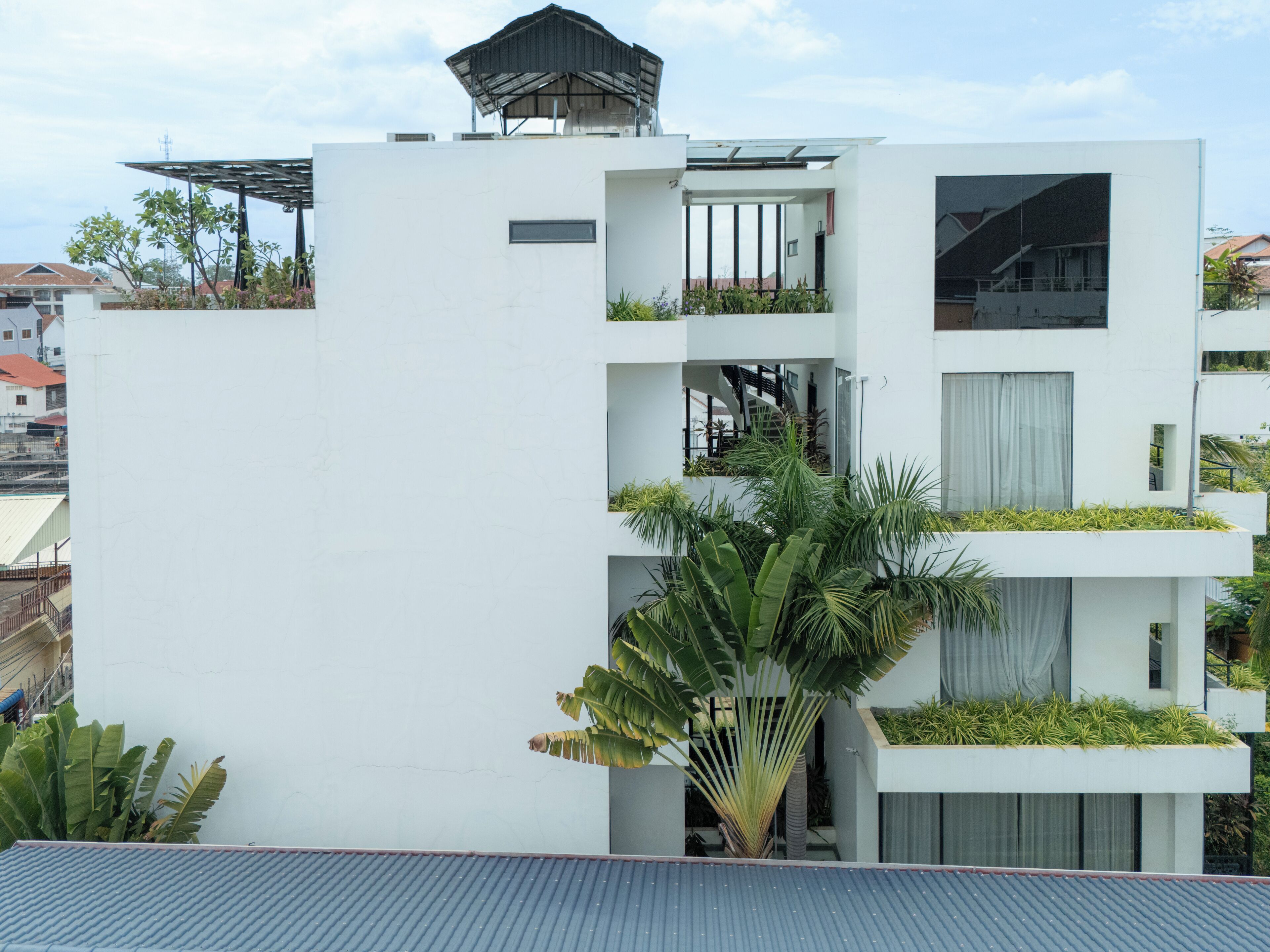 A modern multi-story building with balconies, a covered outdoor area, and a staircase.