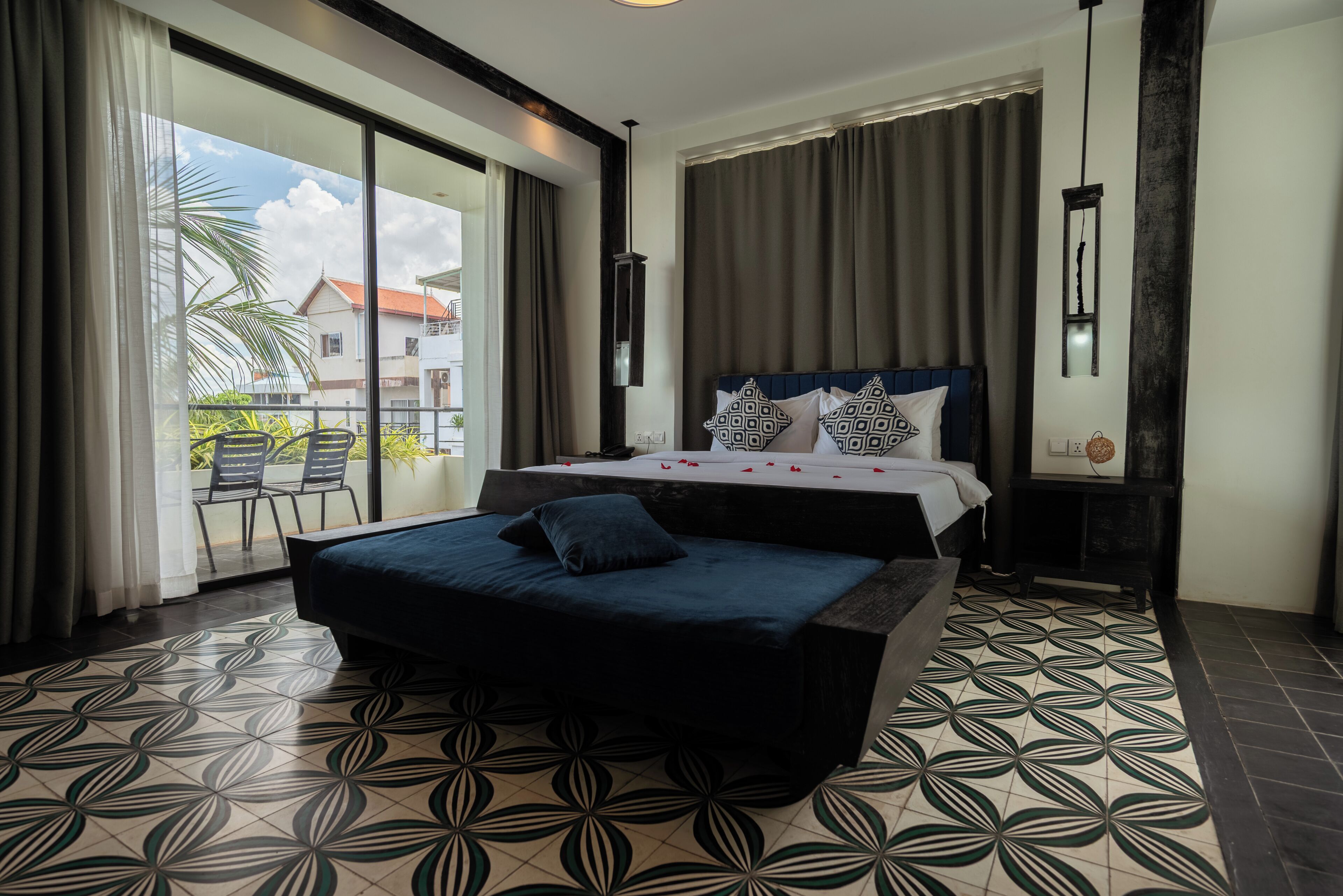 Une chambre d’hôtel avec un lit, un balcon et un sol à motifs.
