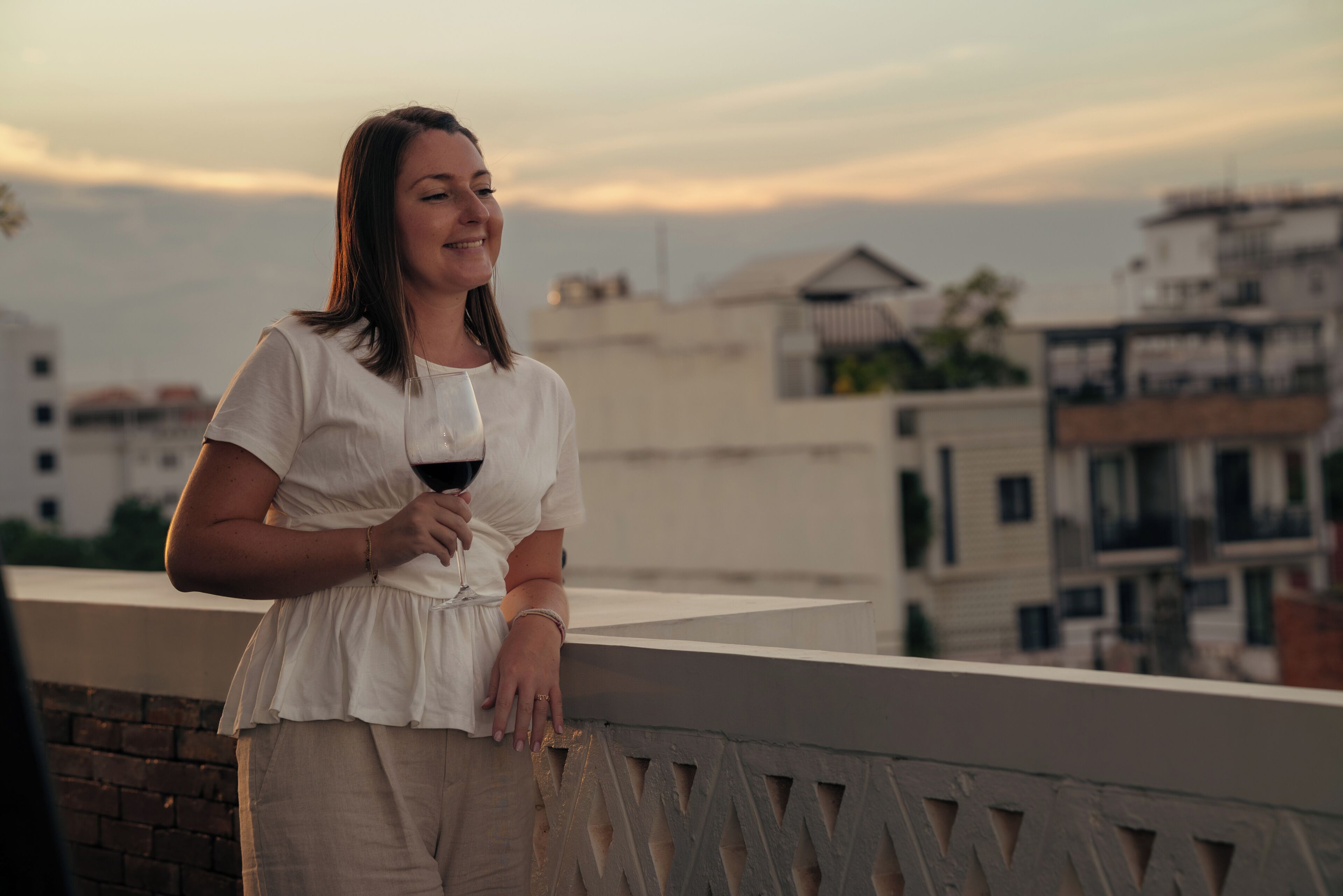 A person standing on a balcony with a cityscape in the background.