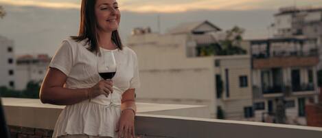 A person standing on a balcony with a cityscape in the background.