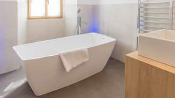 Ein modernes Badezimmer mit einer freistehenden Badewanne, einem Holzkosmetikschrank und einem Handtuch an der Wanne.