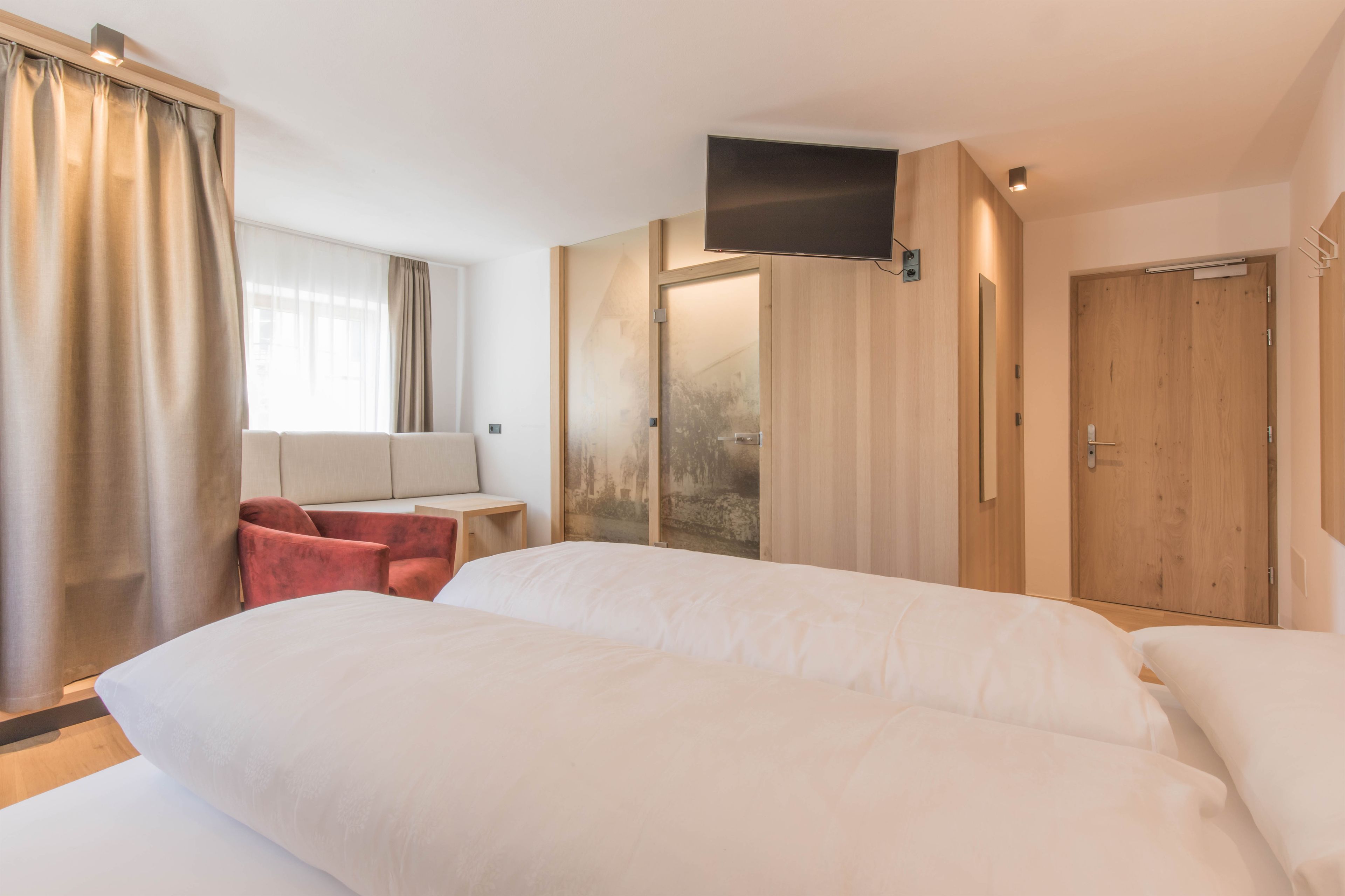 Una camera d'albergo con un letto grande, una scrivania con una sedia, una televisione e un armadio in legno.