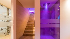 A modern hotel interior with a wooden staircase leading to a purple-lit room.