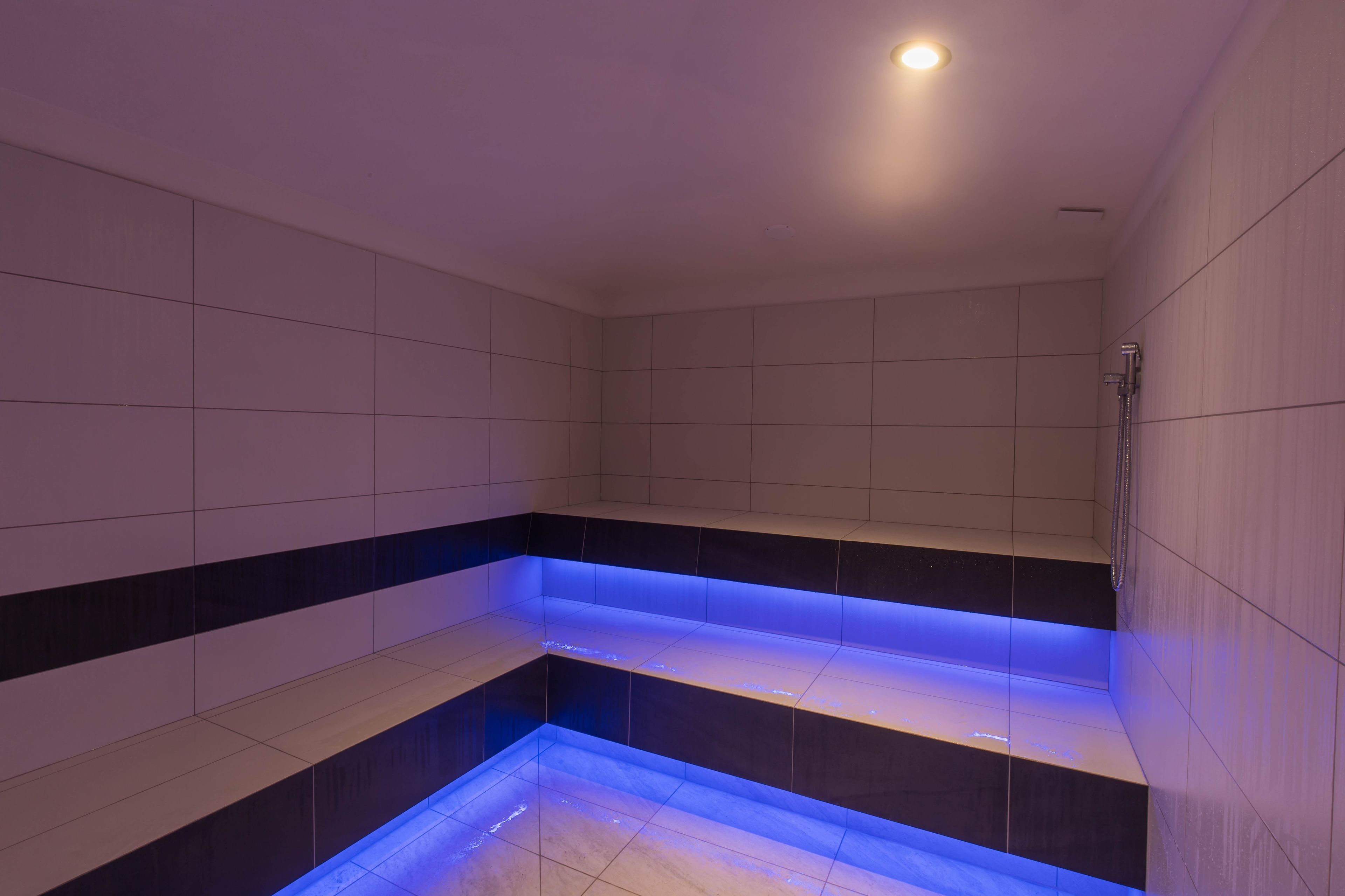A modern bathroom with a blue-lit step feature and a shower area.