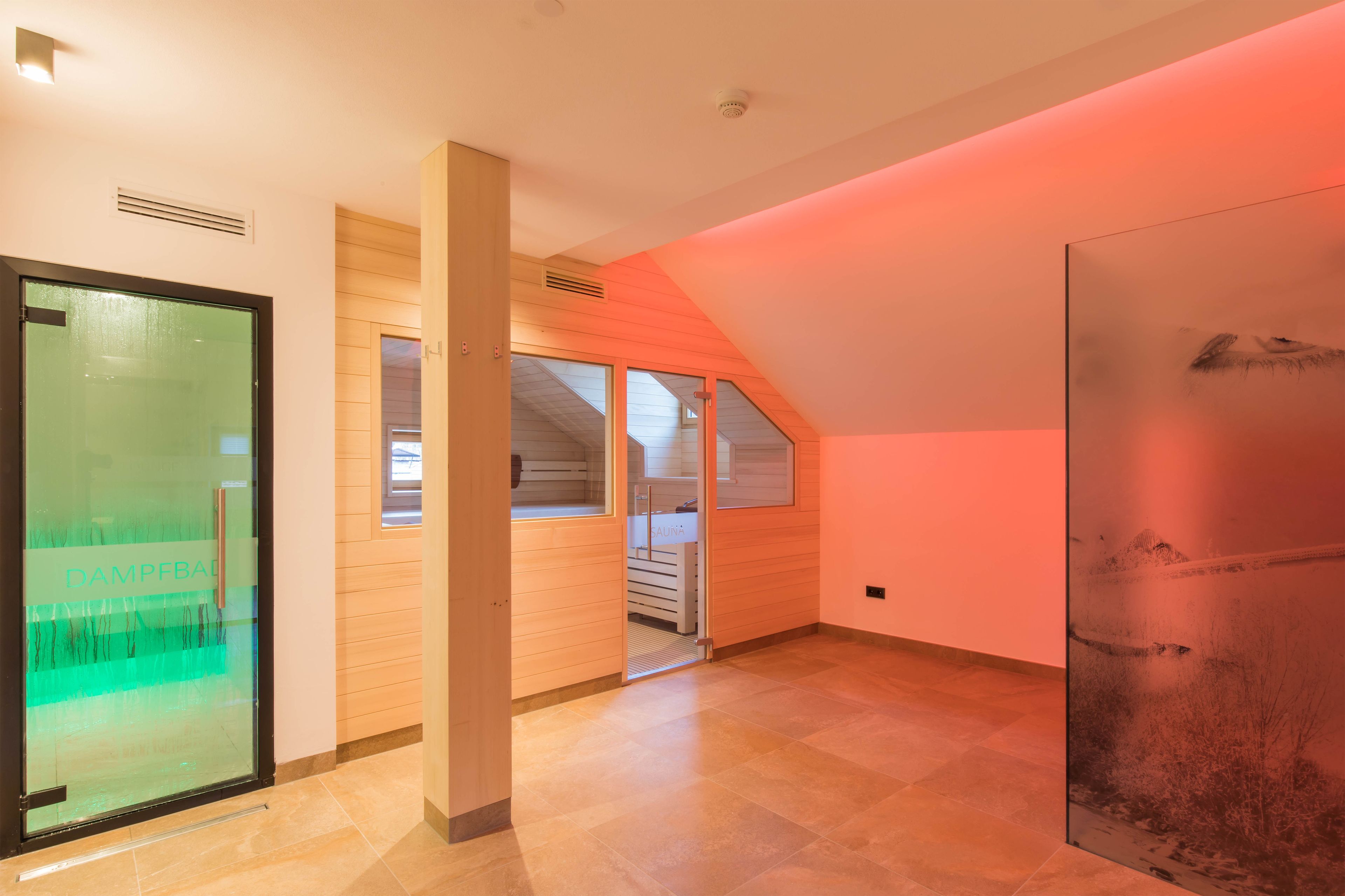A spacious room with a sloped ceiling, a large window, and a glass door with a view of the outside.