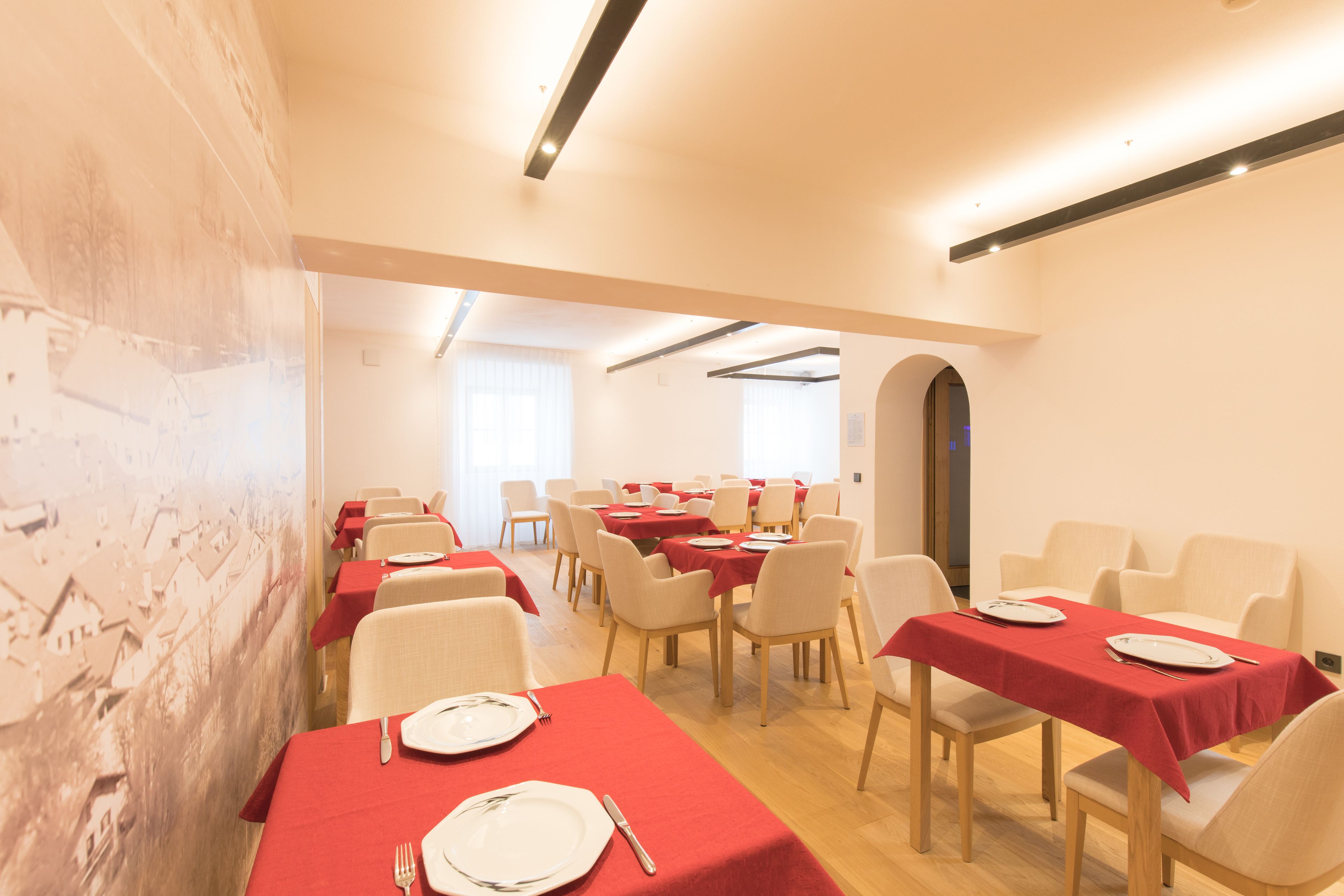 A dining area with tables set for meals, chairs, and a large mural on the wall.
