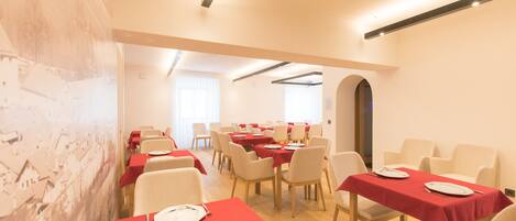 A dining area with tables set for meals, chairs, and a large mural on the wall.