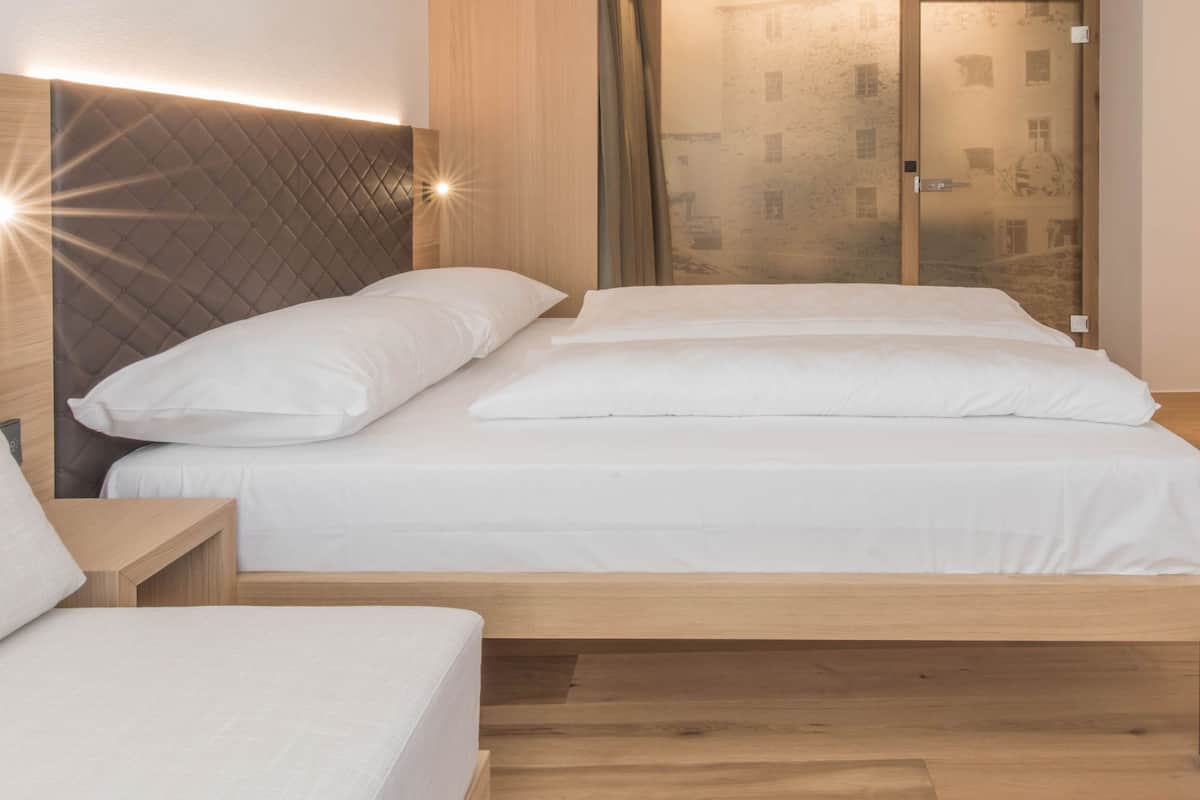 Ein modernes Schlafzimmer mit Holzbettgestell, weißer Bettwäsche und einem Kopfteil mit integrierter Beleuchtung.