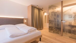 A modern hotel room with a neatly made bed, a large window with curtains, and a wall with a cityscape mural.