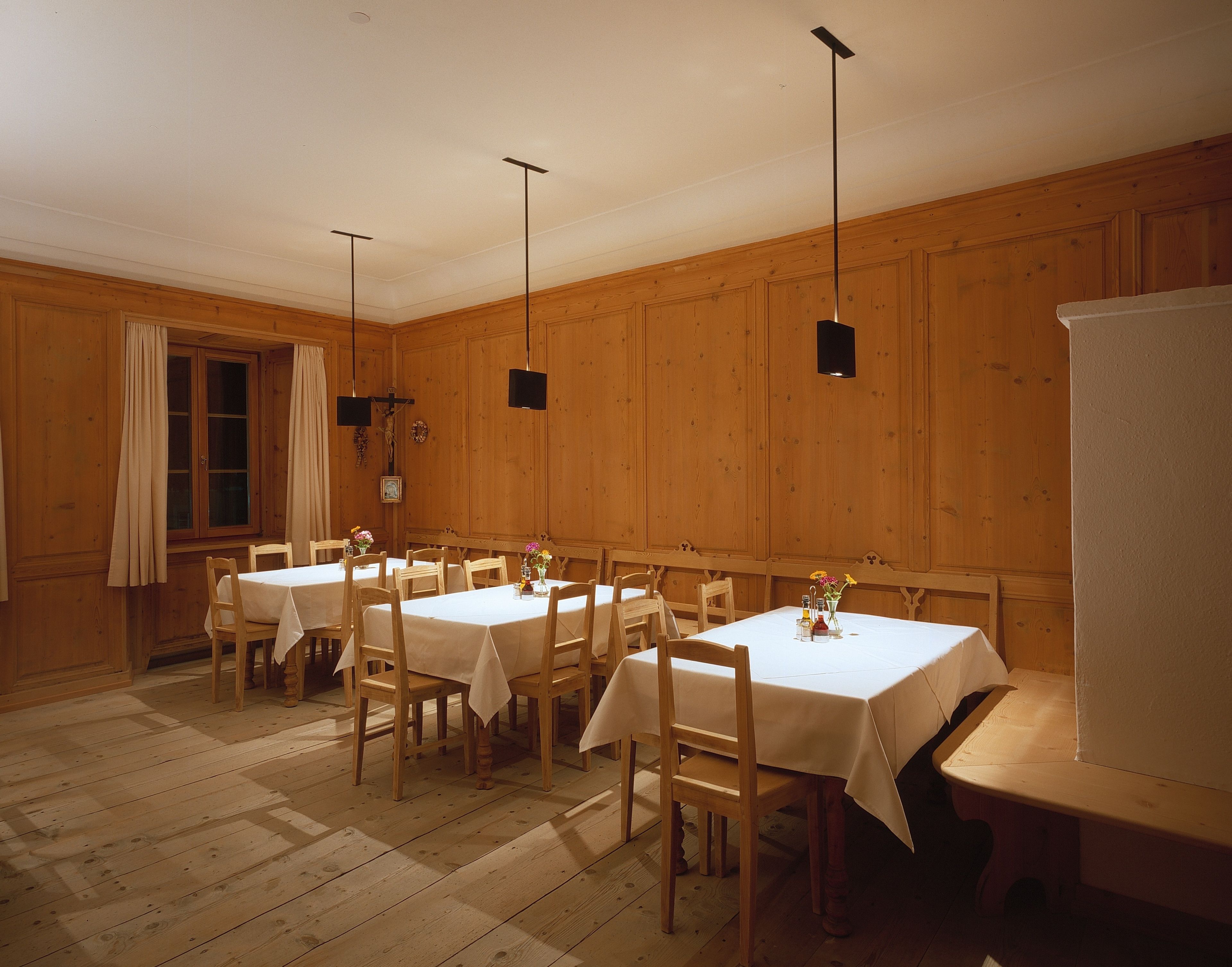 Comedor con paneles de madera, manteles blancos e iluminación colgante sencilla.