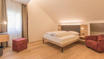 Un dormitorio moderno con cama, un reposapiés rojo, un escritorio y un sillón rojo.