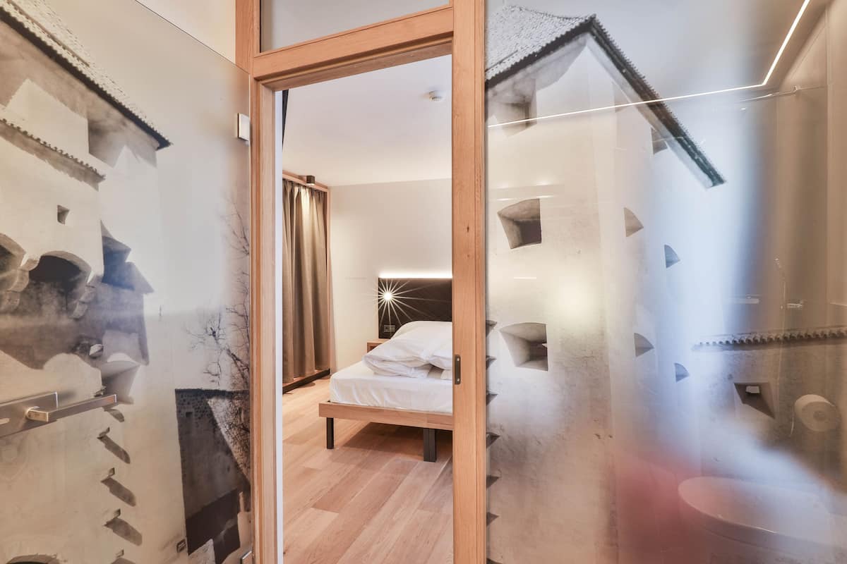 Ein modernes Schlafzimmer mit einem hölzernen Bett, einer Glastür und einer Wand mit geometrischem Muster.