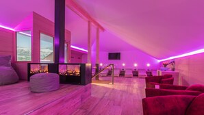 A modern interior with a fireplace, wooden flooring, and red seating.