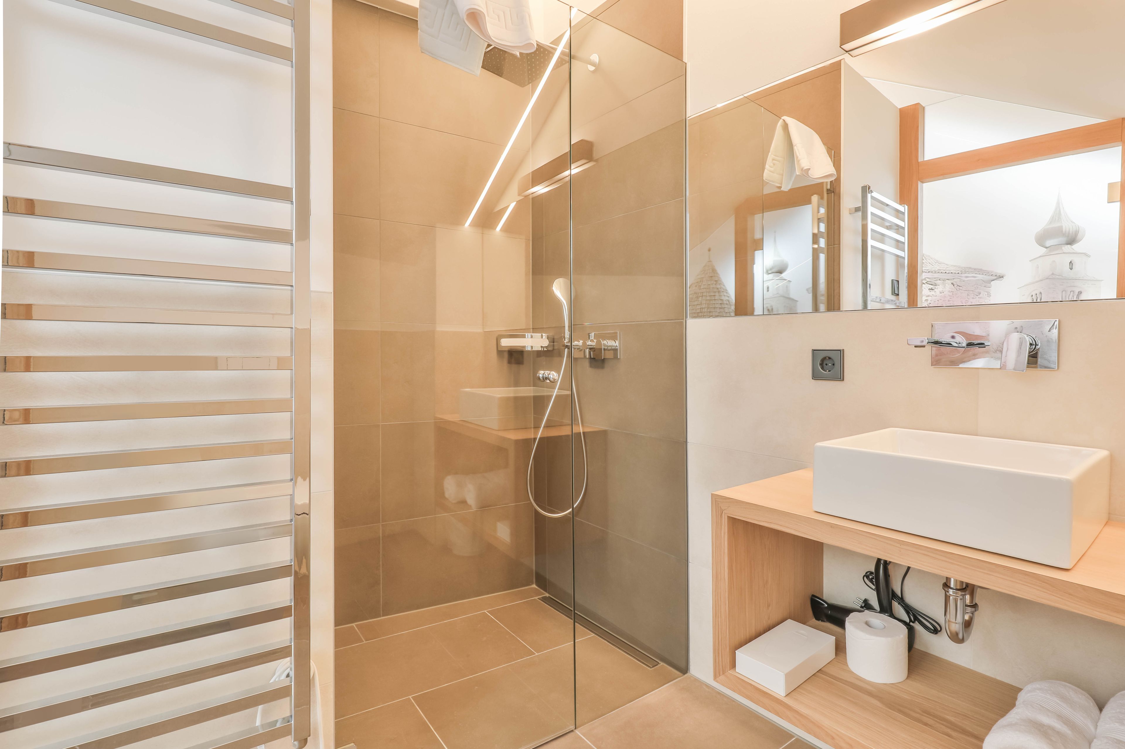 Ein modernes Badezimmer mit einer Duschkabine aus Glas, einem weißen Waschbecken und einem Holzbadezimmer-Möbel.