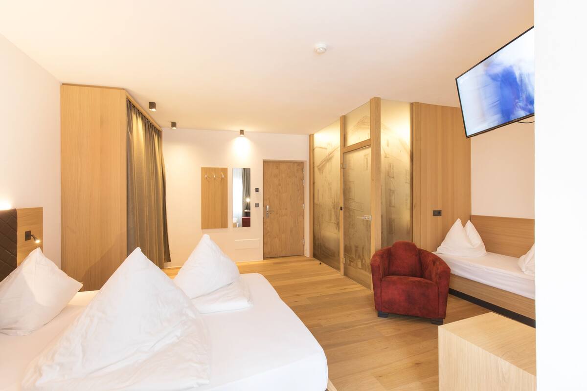 Ein Hotelzimmer mit einem Bett, einem roten Sessel, einem Fernseher und Holzwänden.