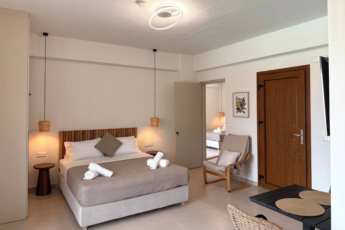 A modern hotel room with a bed, bedside tables, a chair, and a door.