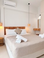 Habitación de hotel con cama, cabecera de madera, aire acondicionado de pared y lámpara de noche.