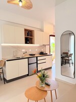 Una cocina moderna con lavavajillas integrado, cafetera y un pequeño comedor con mesa redonda y sillas de mimbre.