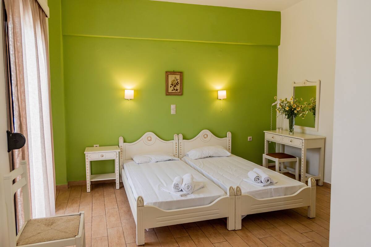A room with two beds, a desk, a chair, and a mirror.