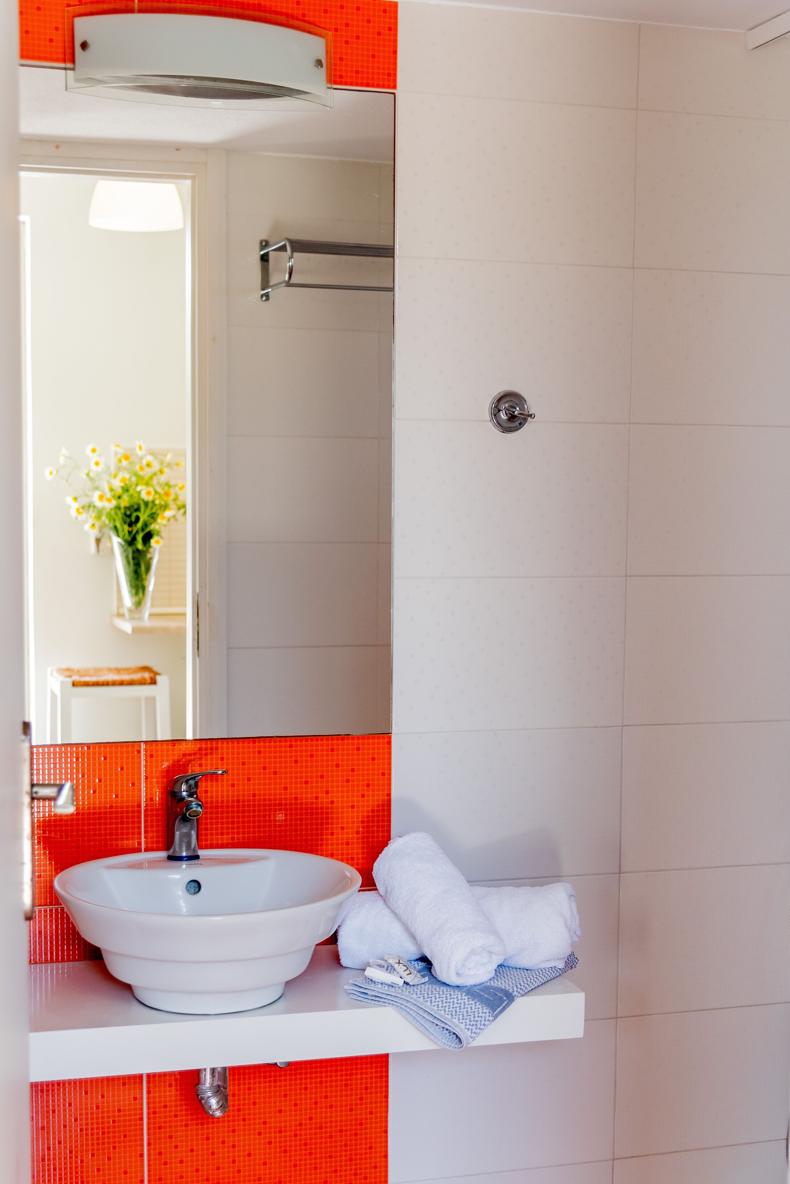 A bathroom with a white sink, a mirror, and a towel rack.