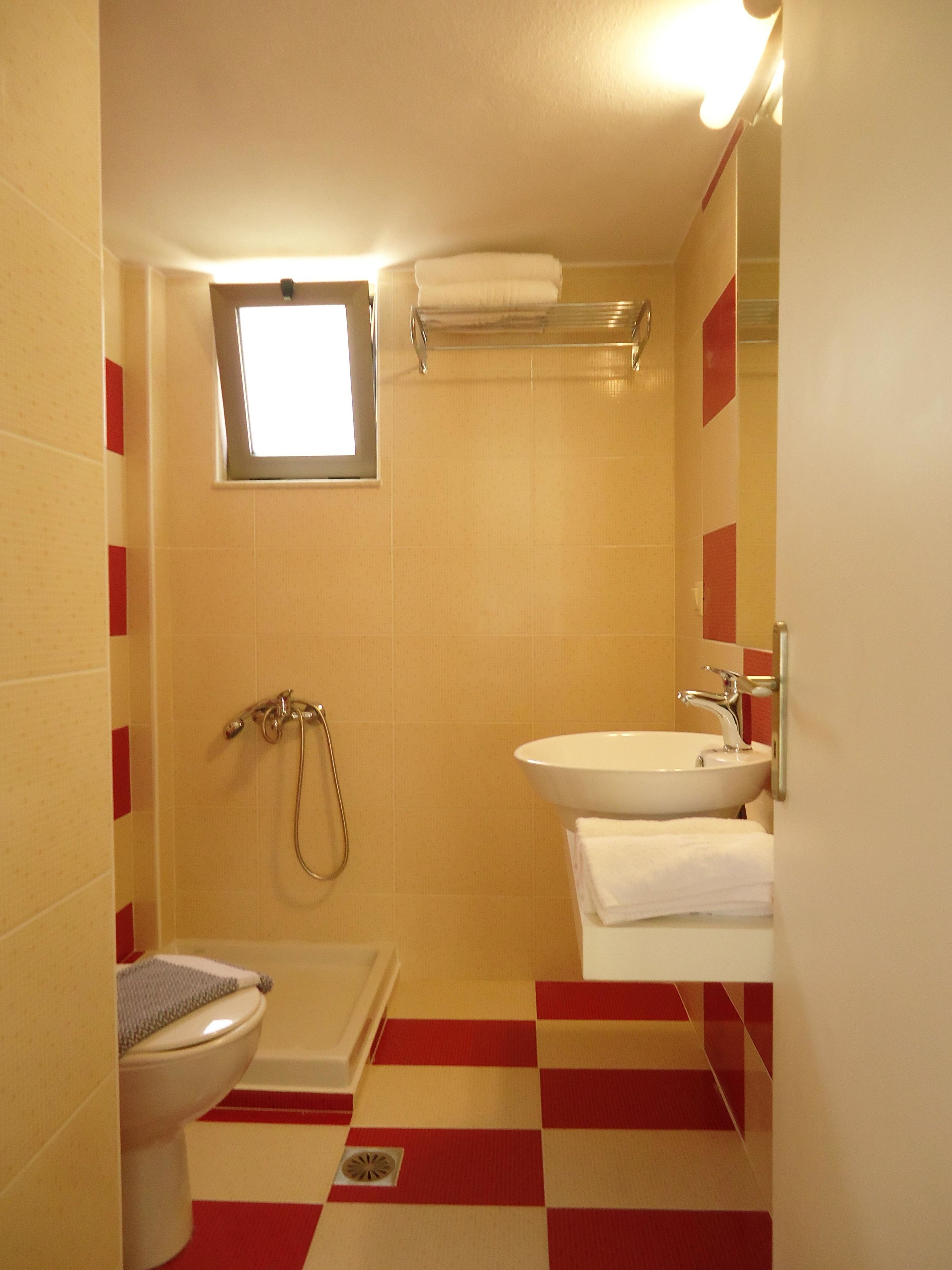 A compact bathroom with a toilet, sink, and shower.