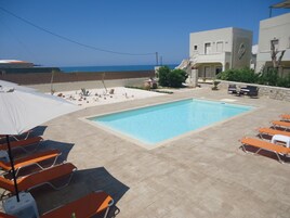 Una piscina al aire libre, sombrillas, sillones reclinables de piscina