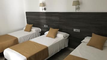 Habitación de hotel con tres camas individuales, cada una con cubrecama marrón y ropa blanca. Hay dos lámparas de pared con abatibles color beige.