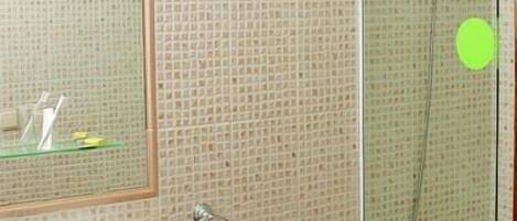 A bathroom with a sink, mirror, and glass-enclosed shower.