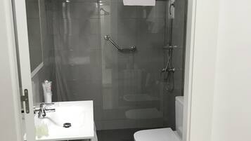 A modern bathroom with a glass-enclosed shower, a white sink, and a toilet.
