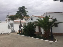 Un edificio blanco con techo de tejas, una escalera y una palmera.
