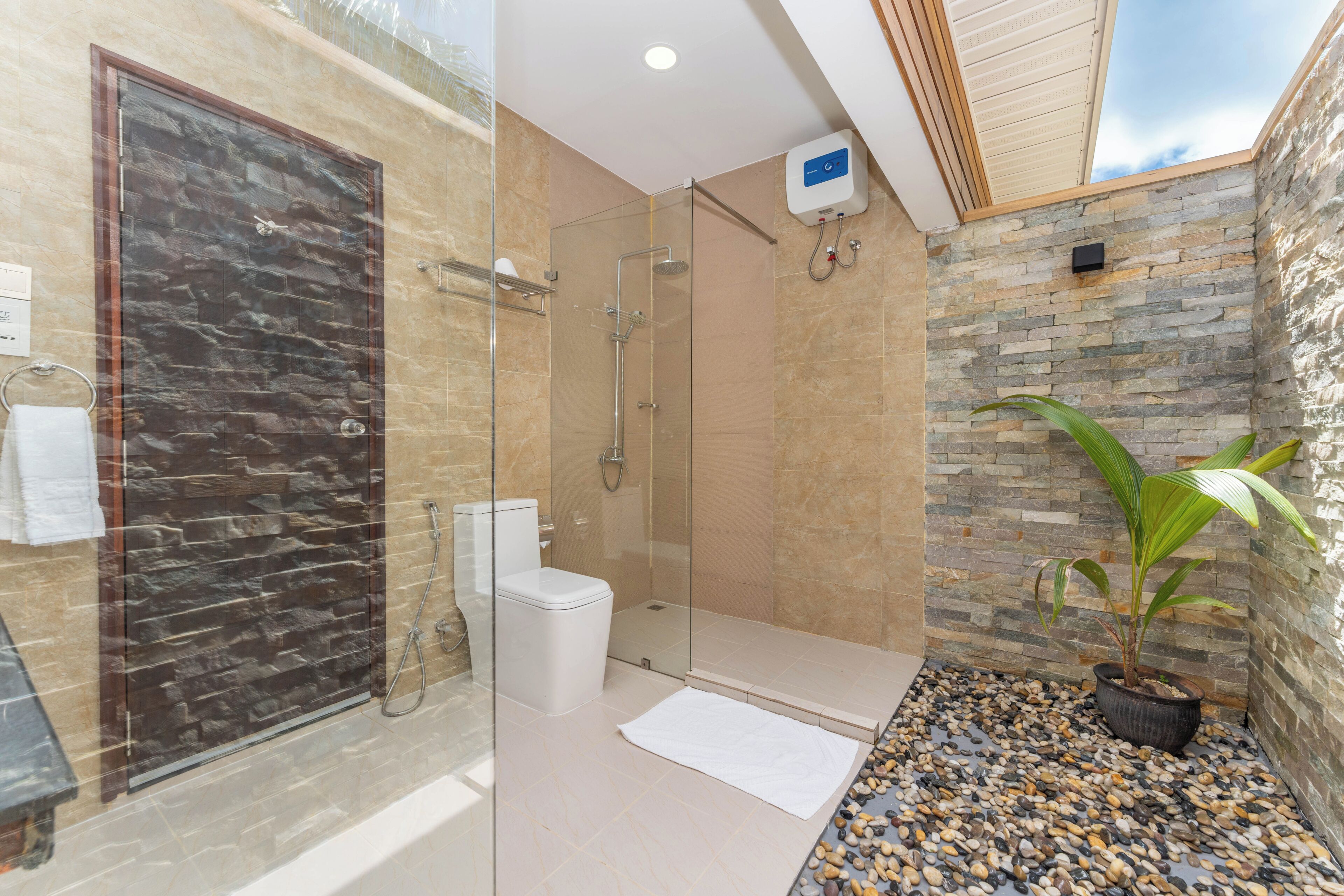 A modern bathroom with a glass-enclosed shower, a toilet, and a stone wall.