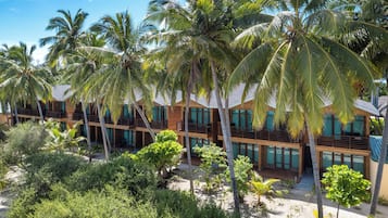 Ein Resort mit mehreren Holzhäusern, jedes mit Balkonen und großen Fenstern, umgeben von Palmen und tropischer Vegetation.