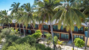Un resort con varias edificaciones de madera, cada una con balcones y ventanas amplias, rodeado de palmeras y vegetación tropical.