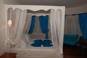 Une chambre avec un lit, une table de chevet, une lampe et une chaise.